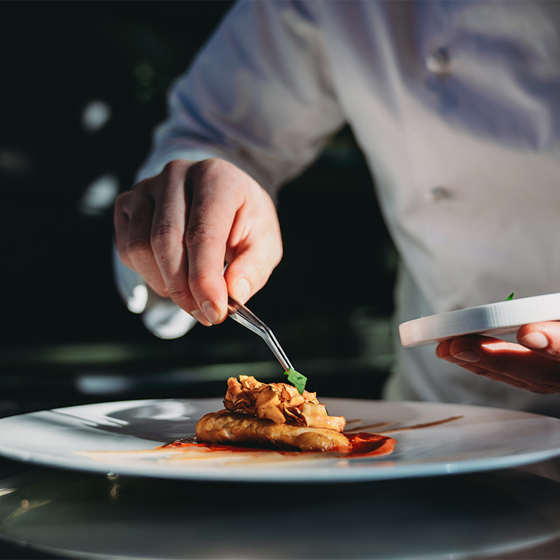 Private chef putting the finishing touches on a dish he's prepared for guests - available when staying at The Butler Collection luxury holiday homes in Sussex