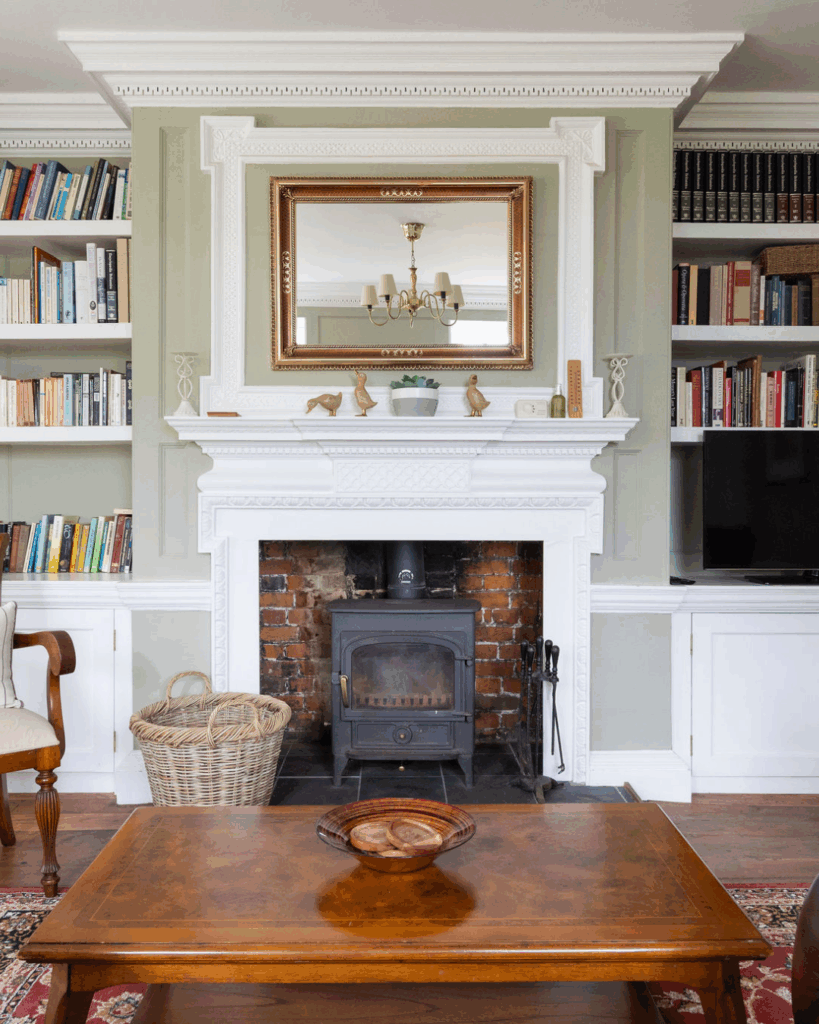 A cosy living room with a log burner, television and book case filled with books.