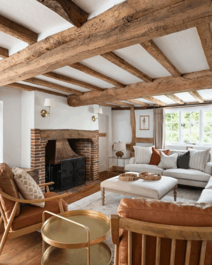 A cosy living room, earthy tones, an open fireplace, exposed wooden beams and lots of natural light.
