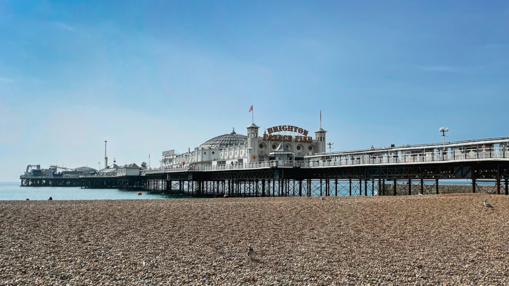 Brighton Palace Pier stretching over the sea on a sunny day, viewed from the pebble beach.