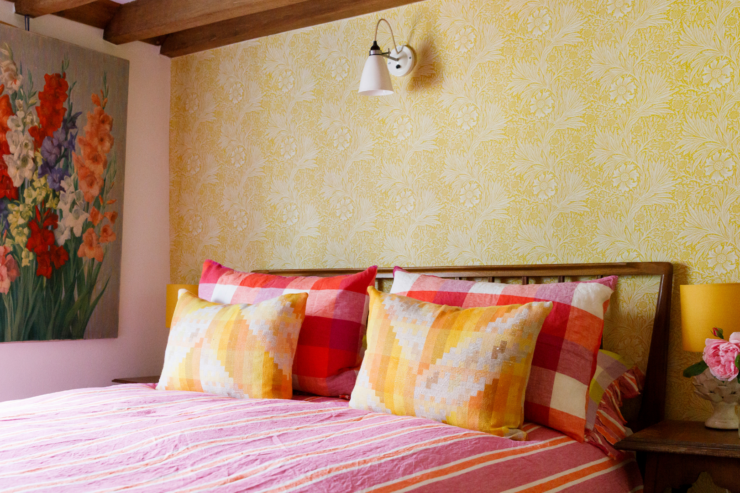 Bright, character-filled bedroom at 15 Bond Street featuring floral wallpaper, colourful cushions, wooden beams and thoughtful vintage styling.