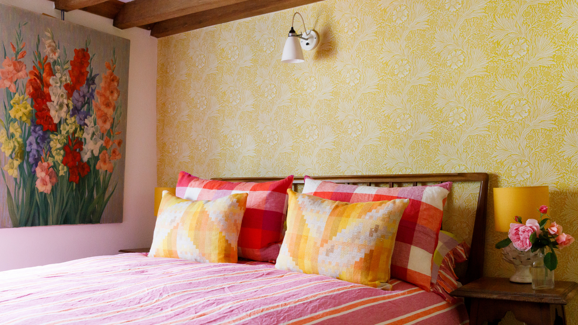 Bright, character-filled bedroom at 15 Bond Street featuring floral wallpaper, colourful cushions, wooden beams and thoughtful vintage styling.
