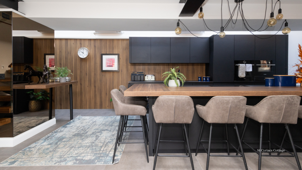 Contemporary open-plan kitchen with dark cabinetry, wooden finishes, pendant lighting and a large island with bar stools.